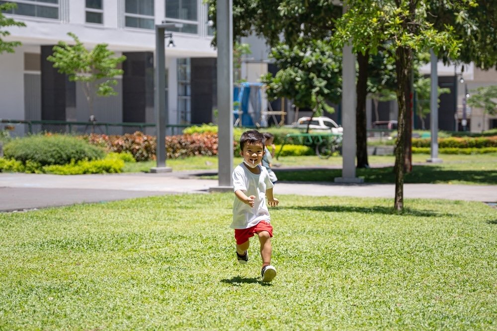 child frolicking in a green space situated in an urban area